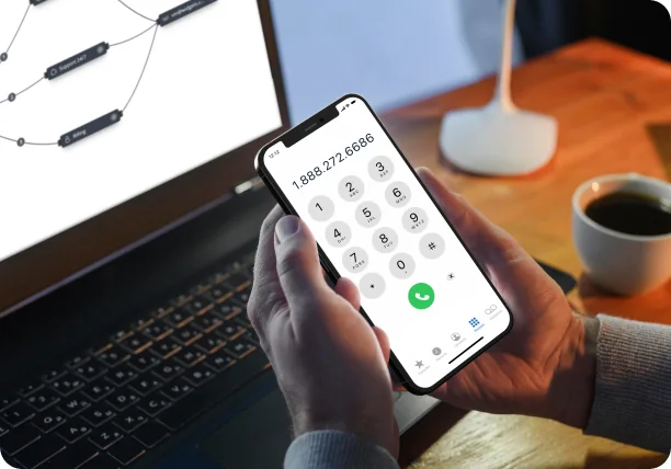 A mobile dialling 1 888 272 6686 in front of a laptop showing a call flow