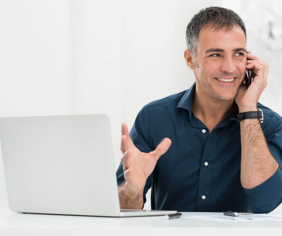 Smiling business professional using a phone and laptop, representing improved communication with the SendMyCall phone.systems app